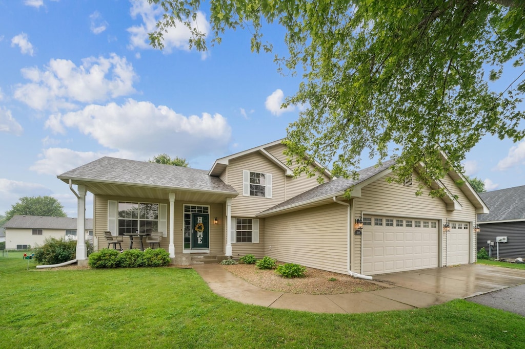 819 Lodge Dr, Jordan, MN 55352 - split level home with an attached garage, driveway, a front lawn, covered porch, and a shingled roof