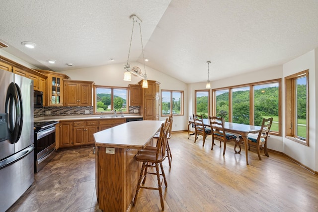 N1931 110th St, Union Twp, WI 54761 - kitchen with stainless steel appliances, brown cabinetry, a textured ceiling, a sink, and lofted ceiling
