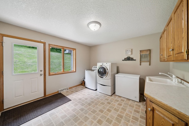 N1931 110th St, Union Twp, WI 54761 - laundry area featuring washing machine and dryer, cabinet space, a textured ceiling, light flooring, and baseboards