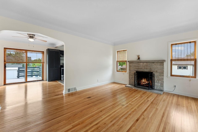 5257 27th Ave S, Minneapolis, MN 55417 - unfurnished living room featuring light wood finished floors, a ceiling fan, a fireplace, baseboards, and arched walkways
