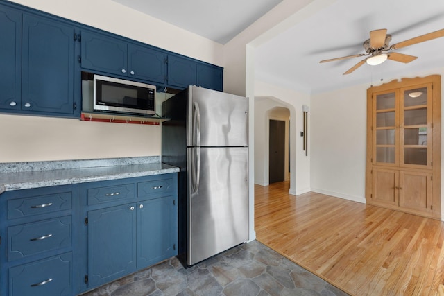 5257 27th Ave S, Minneapolis, MN 55417 - kitchen featuring stainless steel appliances, blue cabinetry, arched walkways, a ceiling fan, and light countertops
