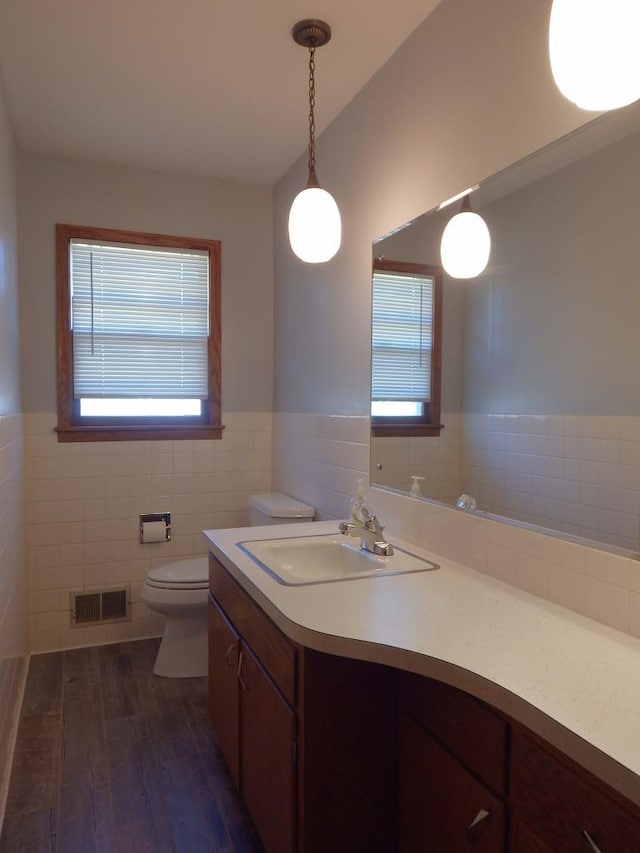 1052 36th Ave N, Saint Cloud, MN 56303 - bathroom featuring toilet, vanity, tile walls, wood finished floors, and a wainscoted wall