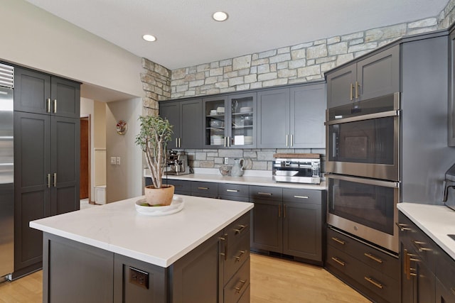 3850 Lone Cedar Ln, Chanhassen, MN 55318 - kitchen featuring appliances with stainless steel finishes, light countertops, light wood finished floors, tasteful backsplash, and glass insert cabinets