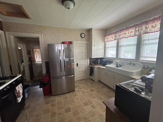 207 Cook St, Palisade, MN 56469 - kitchen featuring freestanding refrigerator, wallpapered walls, white cabinetry, and light countertops
