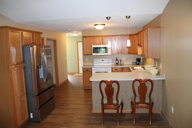 14257 184th Ave NW, Elk River, MN 55330 - kitchen with white appliances, a peninsula, a sink, light countertops, and dark wood-style floors
