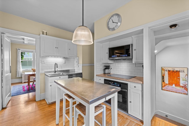 4817 Emerson Ave S, Minneapolis, MN 55419 - kitchen featuring black appliances, radiator heating unit, white cabinets, and tasteful backsplash