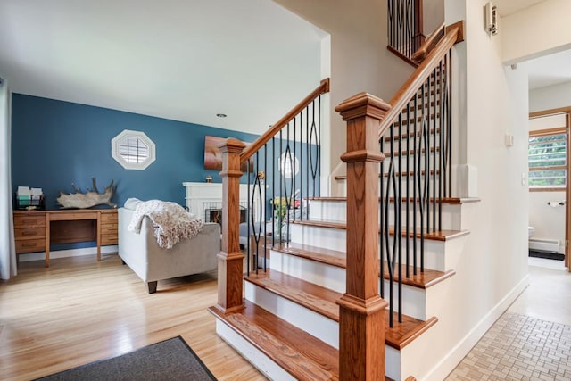 569 Driftwood Rd, New Brighton, MN 55112 - stairs featuring a fireplace, baseboard heating, baseboards, and wood finished floors