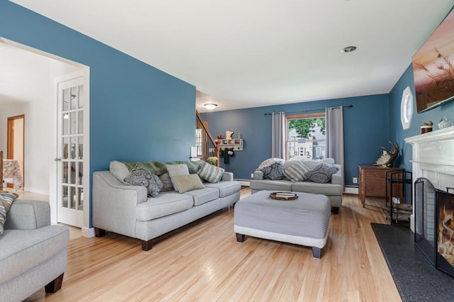569 Driftwood Rd, New Brighton, MN 55112 - living room featuring wood finished floors, a lit fireplace, stairway, a baseboard heating unit, and baseboard heating