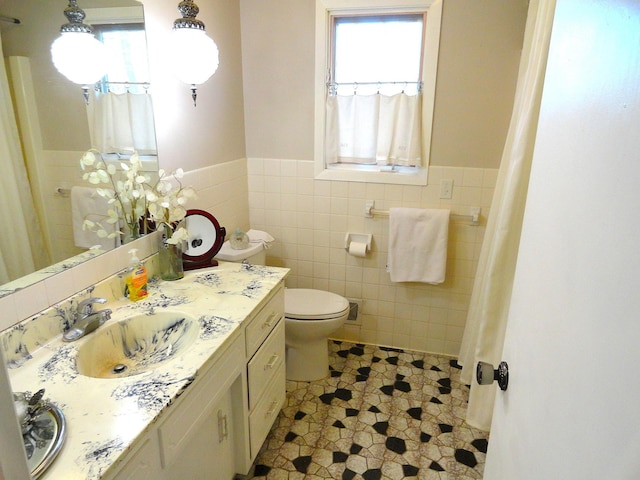 9540 24th Ave N, Plymouth, MN 55441 - full bath featuring healthy amount of natural light, tile walls, wainscoting, vanity, and toilet