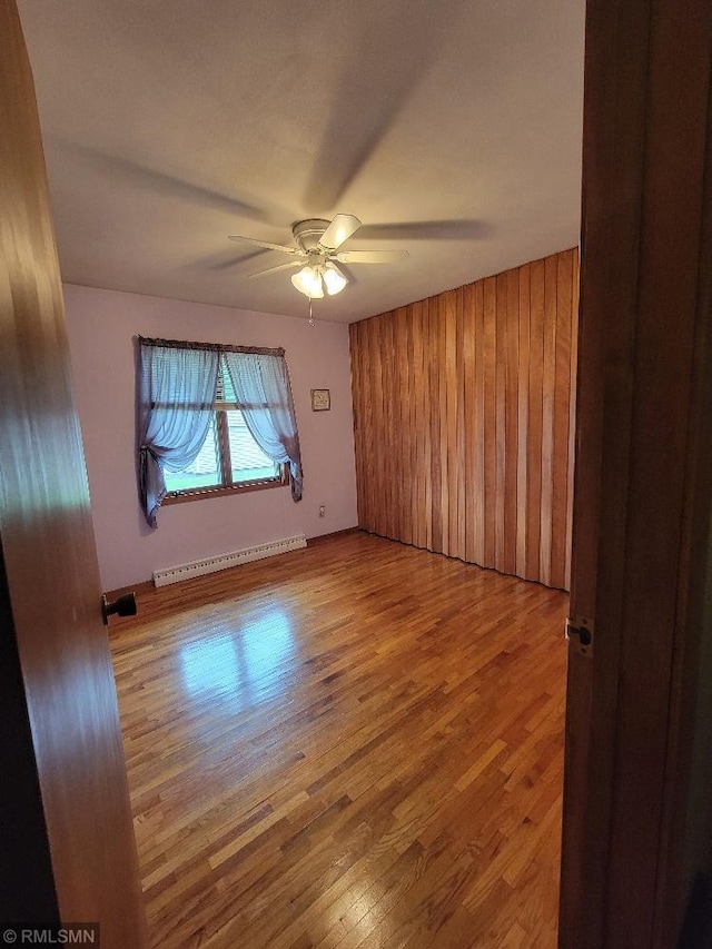 109 Jackson St W, Eagle Bend, MN 56446 - spare room featuring a baseboard radiator, ceiling fan, wood finished floors, and wood walls