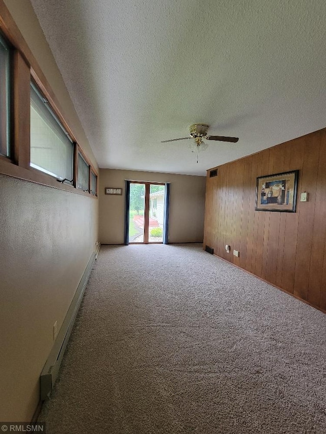 109 Jackson St W, Eagle Bend, MN 56446 - carpeted empty room with a textured ceiling, wood walls, a ceiling fan, and baseboards