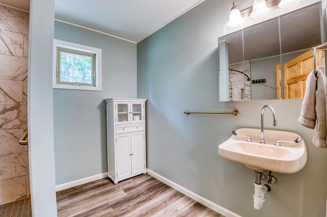 15989 Lost Oaks Dr SE, Cass Lake, MN 56633 - bathroom featuring wood finished floors, a tile shower, baseboards, and a sink