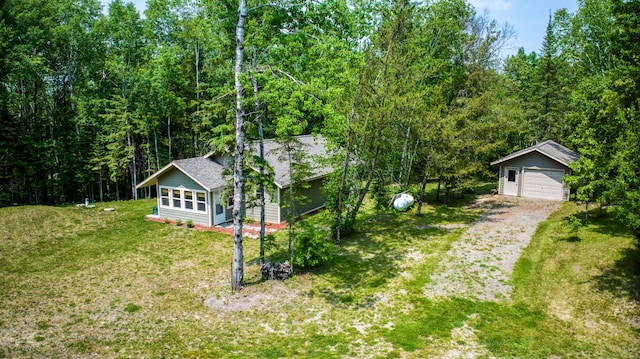 15989 Lost Oaks Dr SE, Cass Lake, MN 56633 - view of green lawn featuring an outbuilding, a forest view, a detached garage, and dirt driveway