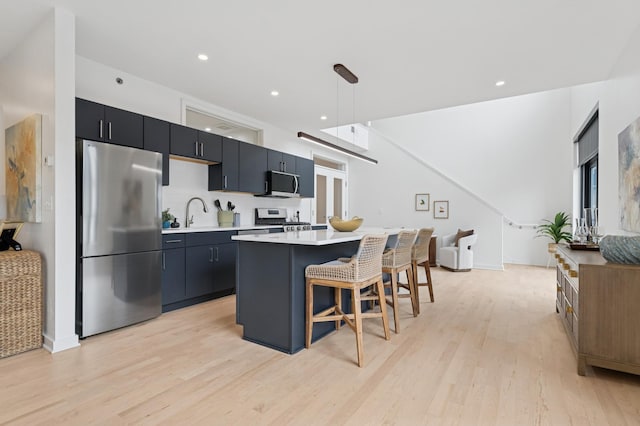 3104 Lake St Unit 412, Minneapolis, MN 55416 - kitchen with stainless steel appliances, light wood-style flooring, a kitchen bar, light countertops, and a kitchen island