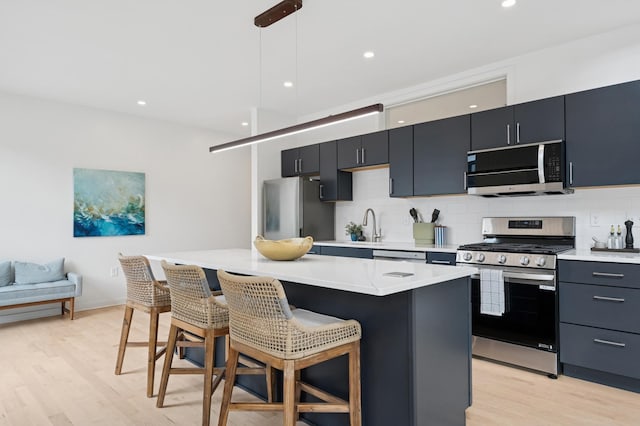 3104 Lake St Unit 412, Minneapolis, MN 55416 - kitchen with appliances with stainless steel finishes, a breakfast bar area, light wood-style floors, backsplash, and recessed lighting