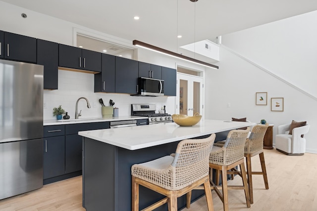 3104 Lake St Unit 412, Minneapolis, MN 55416 - kitchen with stainless steel appliances, a breakfast bar area, light countertops, light wood-style flooring, and backsplash
