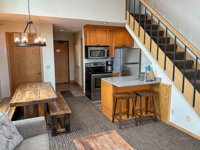 122 Bridge Run Ln Unit A, Lutsen Twp, MN 55615 - kitchen with stainless steel appliances, a chandelier, brown cabinetry, a peninsula, and baseboards