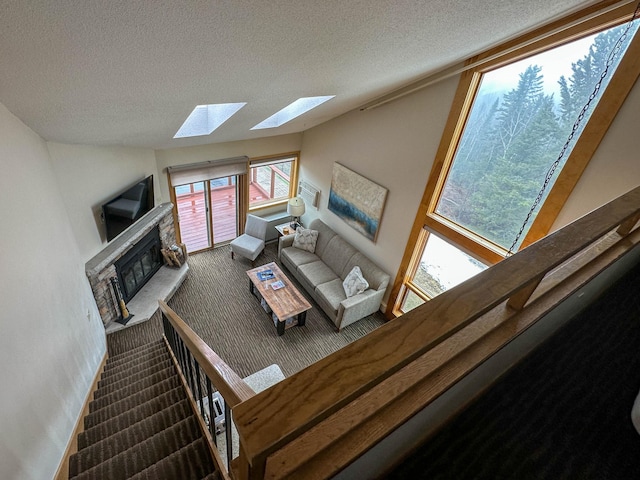 122 Bridge Run Ln Unit A, Lutsen Twp, MN 55615 - carpeted living room with a skylight, a textured ceiling, a stone fireplace, and vaulted ceiling