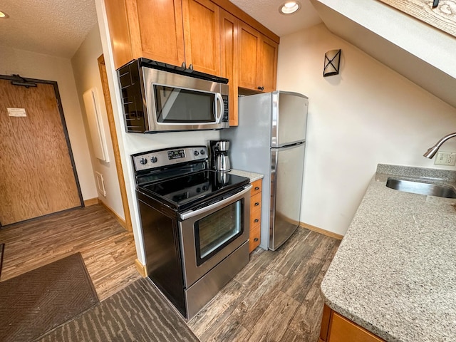 122 Bridge Run Ln Unit A, Lutsen Twp, MN 55615 - kitchen with appliances with stainless steel finishes, a sink, brown cabinetry, dark wood-style floors, and a textured ceiling