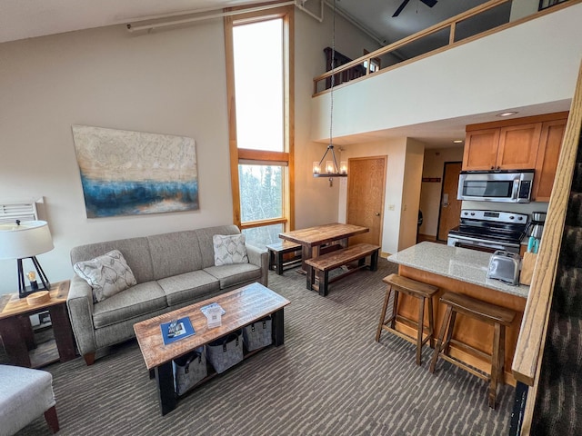 122 Bridge Run Ln Unit A, Lutsen Twp, MN 55615 - living room with dark colored carpet, a towering ceiling, a chandelier, and a ceiling fan