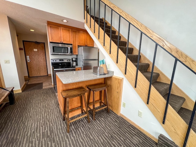 122 Bridge Run Ln Unit A, Lutsen Twp, MN 55615 - kitchen with appliances with stainless steel finishes, dark carpet, brown cabinets, baseboards, and recessed lighting