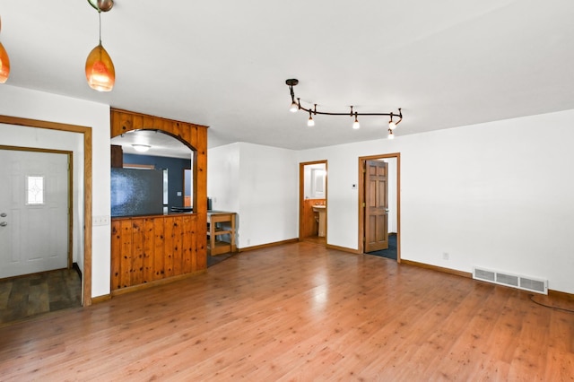 618 Park St, Alexandria, MN 56308 - unfurnished living room featuring wood finished floors, baseboards, arched walkways, and track lighting