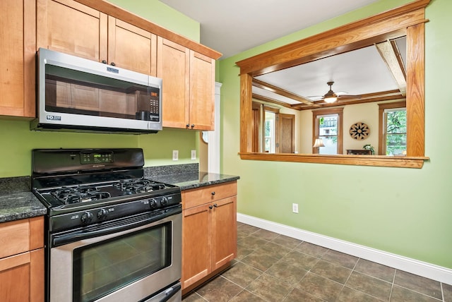 1112 25th St Unit 203, Minneapolis, MN 55405 - kitchen with appliances with stainless steel finishes, baseboards, ceiling fan, dark tile patterned flooring, and dark stone counters