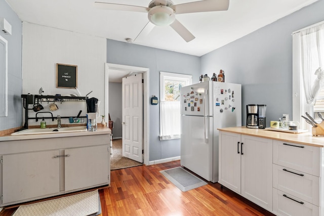 662 24th Ave NE, Minneapolis, MN 55418 - kitchen featuring freestanding refrigerator, ceiling fan, light wood-style flooring, and white cabinetry