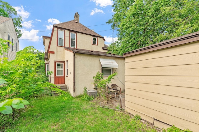 662 24th Ave NE, Minneapolis, MN 55418 - back of house featuring stucco siding, entry steps, a chimney, and cooling unit