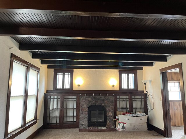 845 12th St, Windom, MN 56101 - carpeted living area with beamed ceiling, a stone fireplace, and baseboards