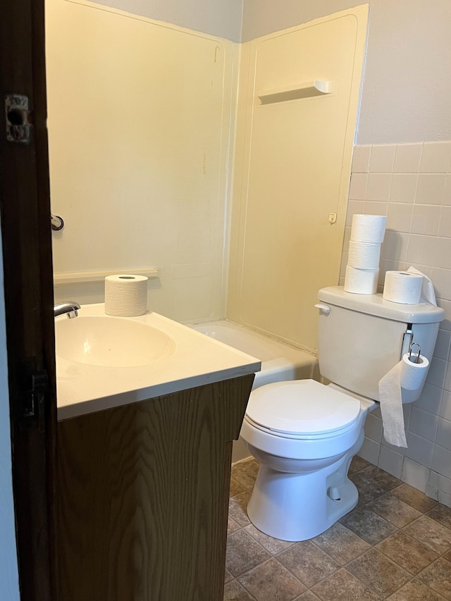 845 12th St, Windom, MN 56101 - full bathroom with vanity, tile walls, toilet, and stone finish floors