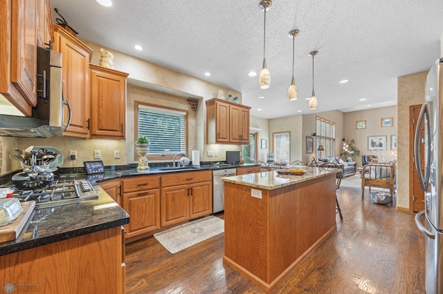 117 50th Ave E, Fargo, ND 58078 - kitchen featuring appliances with stainless steel finishes, a textured ceiling, dark wood-type flooring, recessed lighting, and an island with sink