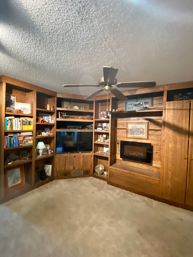 1004 9th St 1006, International Falls, MN 56649 - unfurnished living room featuring a glass covered fireplace, a ceiling fan, carpet, and a textured ceiling