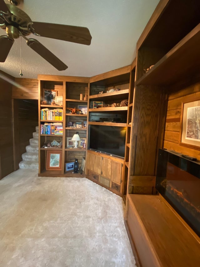 1004 9th St 1006, International Falls, MN 56649 - unfurnished living room with a ceiling fan, stairway, wood walls, and carpet