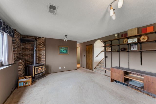 7567 Lent Trl, Lent Twp, MN 55079 - unfurnished living room featuring light colored carpet, a wood stove, stairs, and a textured ceiling