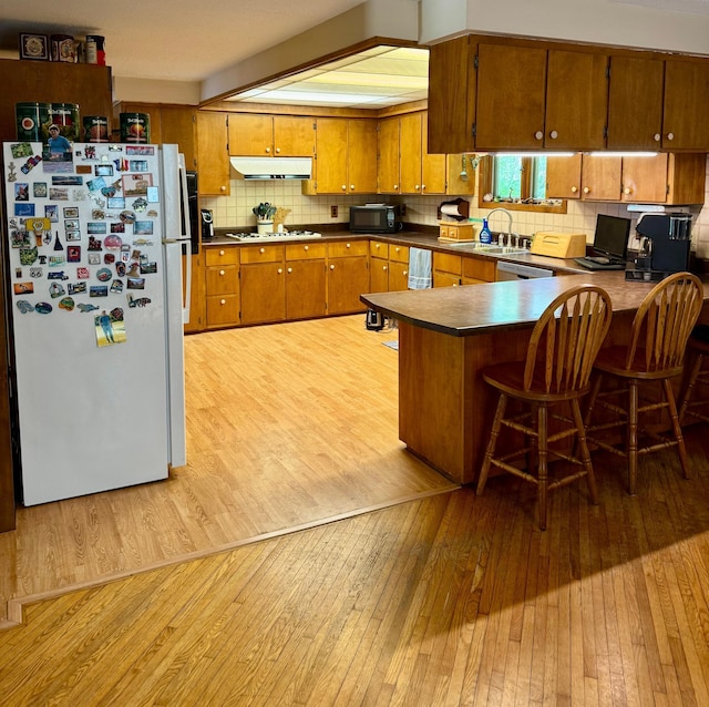 1831 State Highway 11 SE, Gudrid Twp, MN 56623 - kitchen with white appliances, brown cabinetry, light wood-style flooring, a peninsula, and backsplash
