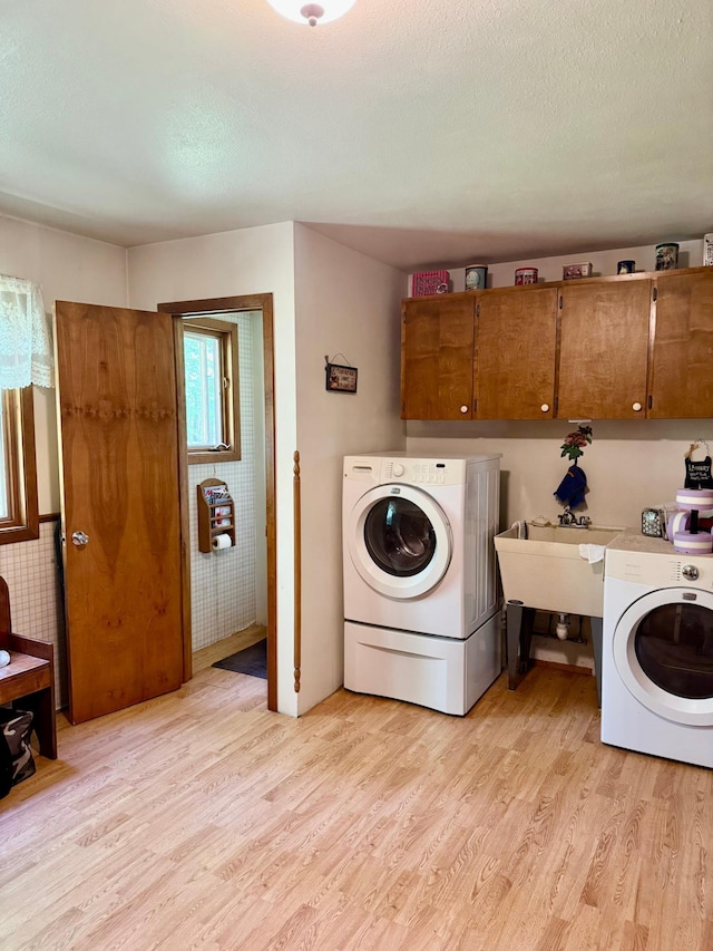 1831 State Highway 11 SE, Gudrid Twp, MN 56623 - washroom with cabinet space, light wood finished floors, washer and clothes dryer, and a textured ceiling