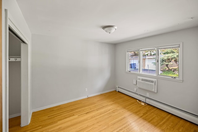 4922 Sheridan Ave S, Minneapolis, MN 55410 - unfurnished bedroom featuring a baseboard radiator, light wood-style flooring, an AC wall unit, baseboards, and a closet