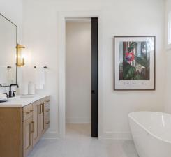full bathroom featuring double vanity, a soaking tub, and baseboards