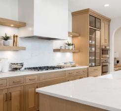kitchen featuring arched walkways, gas cooktop, tasteful backsplash, light countertops, and open shelves