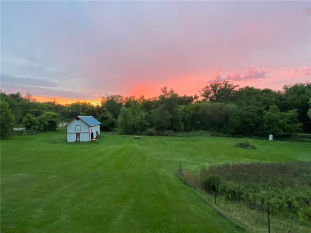 yard at dusk featuring a yard, an outdoor structure, and a view of countryside