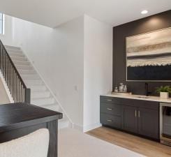 bar with stairway, wine cooler, recessed lighting, and light wood-style floors