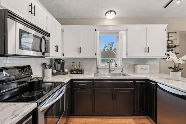 20561 Jade Cir, Lakeville, MN 55044 - kitchen with stainless steel appliances, a sink, a textured ceiling, white cabinets, and light stone counters