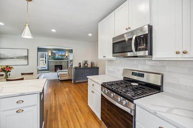 1372 Victoria St N, Saint Paul, MN 55117 - kitchen with appliances with stainless steel finishes, open floor plan, tasteful backsplash, a lit fireplace, and white cabinetry