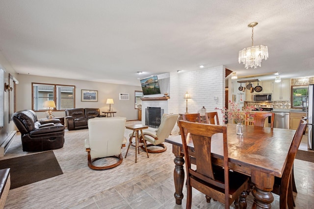 3886 Eagle Rd, Willmar, MN 56201 - dining area with a brick fireplace, a chandelier, a textured ceiling, and baseboard heating