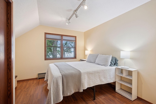 3886 Eagle Rd, Willmar, MN 56201 - bedroom featuring a baseboard radiator, rail lighting, vaulted ceiling, and wood finished floors