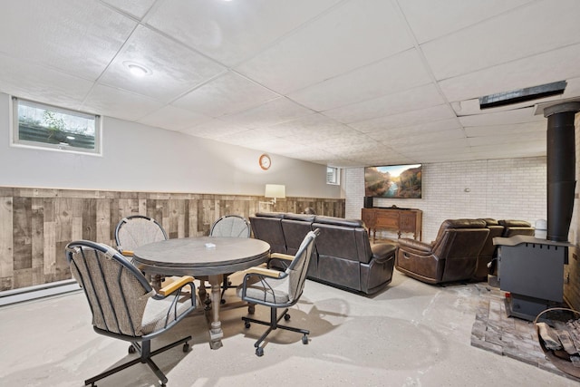 3886 Eagle Rd, Willmar, MN 56201 - dining area featuring a drop ceiling, finished concrete flooring, a wood stove, wainscoting, and baseboard heating