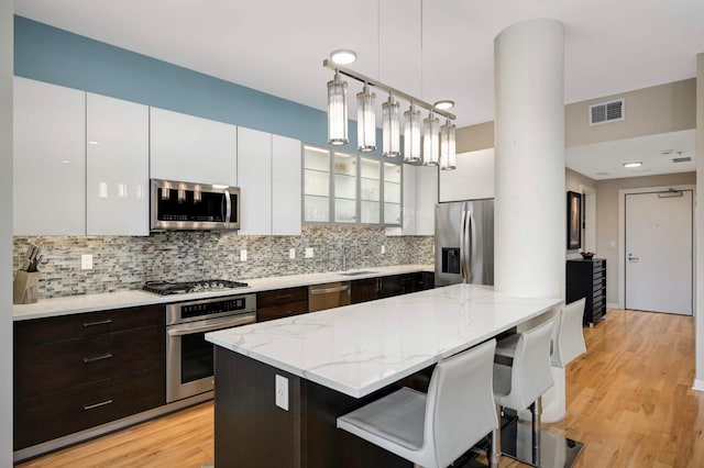 1240 2nd St Unit 1120, Minneapolis, MN 55415 - kitchen featuring stainless steel appliances, white cabinetry, tasteful backsplash, and dark brown cabinetry