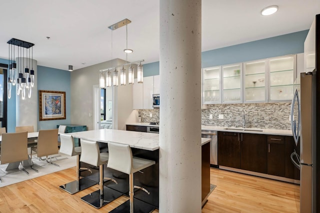 1240 2nd St Unit 1120, Minneapolis, MN 55415 - kitchen with a sink, stainless steel appliances, light wood-style floors, tasteful backsplash, and dark brown cabinetry