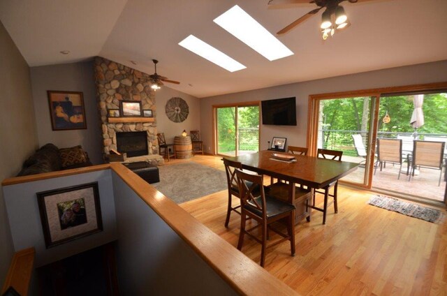 12207 285th St, Lindstrom, MN 55045 - dining space featuring ceiling fan, vaulted ceiling, a stone fireplace, light wood-type flooring, and a skylight